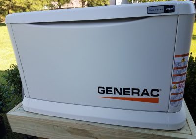 Large white Generac Guardian 22kW generator on a wooden platform outdoors with warning labels visible.